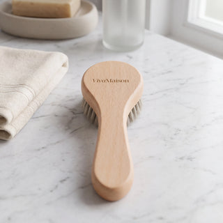 Natural bristle dry face brush on a bathroom shelf with towels and a candle - VivaMaison