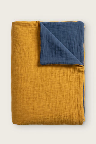 Reversible two-tone muslin duvet cover in mustard / indigo blue, folded view showing both sides