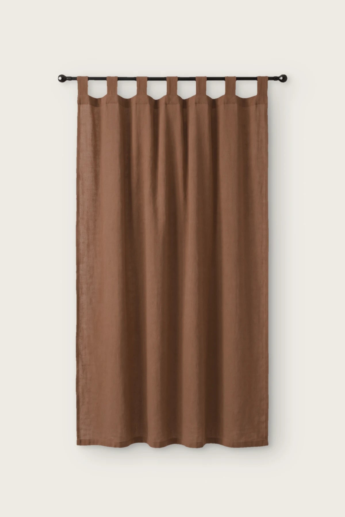Stonewashed cotton curtain panel in brown, single tab top panel on a black rod, front view