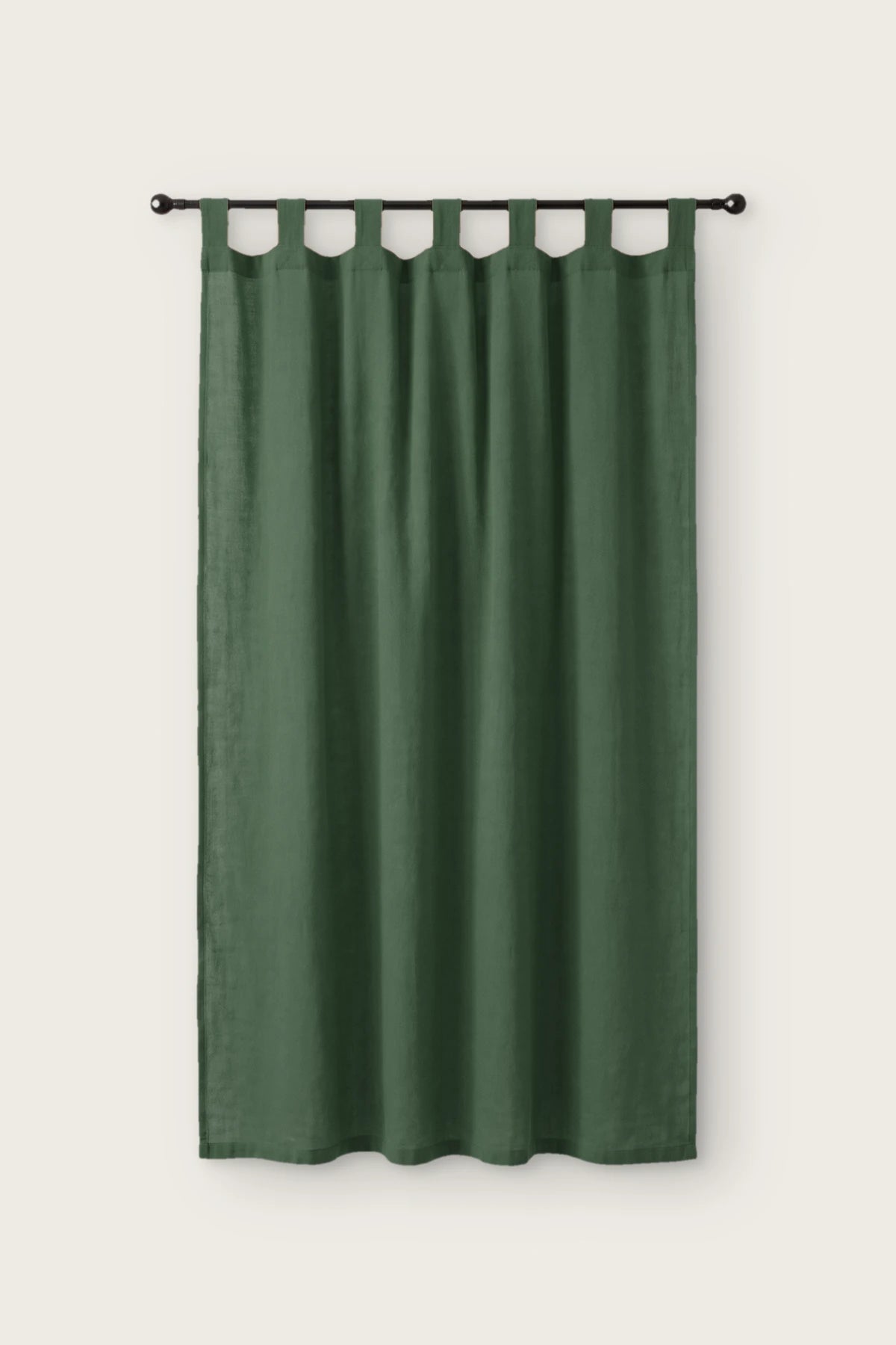 Stonewashed cotton curtain panel in dark green, single tab top panel on a black rod, front view