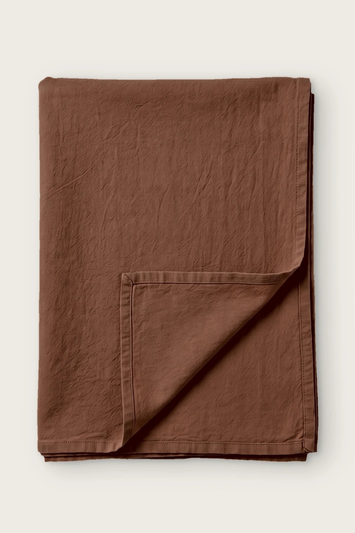 Brown handwoven stonewashed Turkish cotton tablecloth, folded with corner turned back. Vintage-soft Denizli, OEKO-TEX. VivaMaison