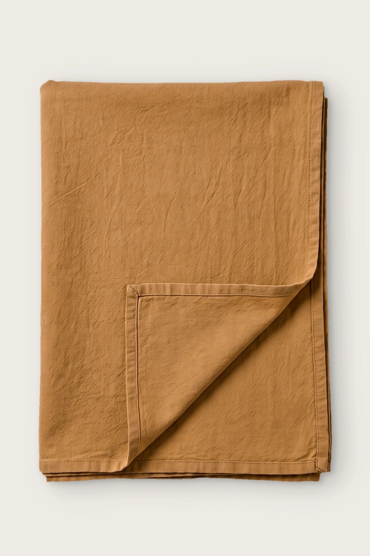 Caramel handwoven stonewashed Turkish cotton tablecloth, folded with corner turned back. Vintage-soft Denizli, OEKO-TEX. VivaMaison