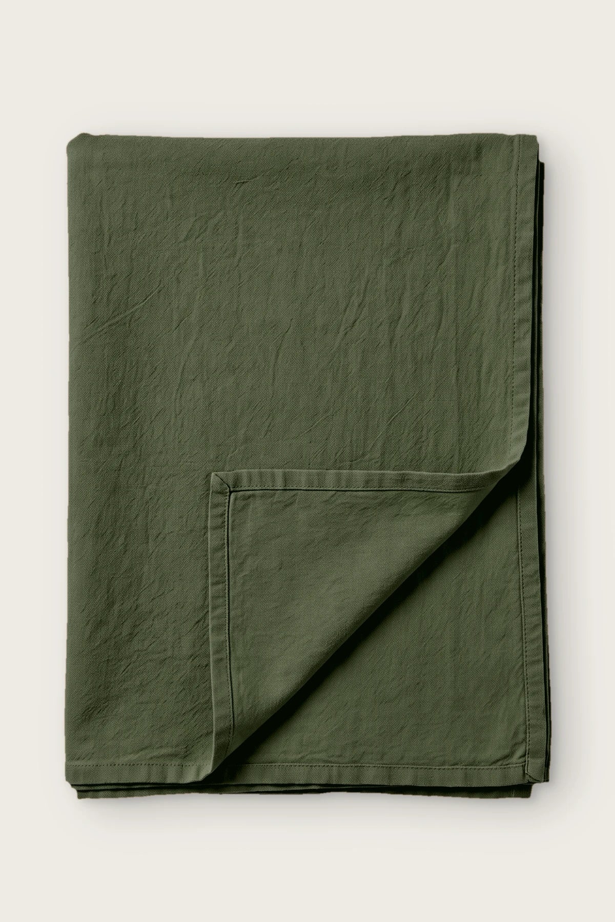Green handwoven stonewashed Turkish cotton tablecloth, folded with corner turned back. Vintage-soft Denizli, OEKO-TEX. VivaMaison