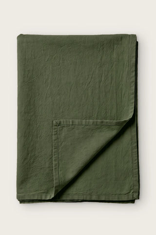 Green handwoven stonewashed Turkish cotton tablecloth, folded with corner turned back. Vintage-soft Denizli, OEKO-TEX. VivaMaison
