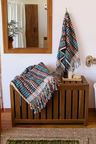 Rainbow Turkish cotton mosaic towel in a bathroom, hanging and draped over a wooden chest - VivaMaison