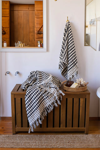 Anthracite White Turkish cotton pom pom towel in a bathroom, hanging and draped over a wooden chest - VivaMaison