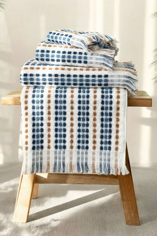 Blue Brown Turkish cotton pom pom towel stacked with one towel draped over the edge - VivaMaison