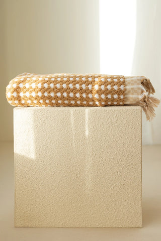Mustard Turkish cotton pom pom towel folded on a plinth - VivaMaison