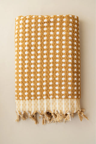 Mustard Turkish cotton pom pom towel folded front view with bobble texture and knotted fringe - VivaMaison