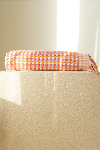 Orange Pink Turkish cotton pom pom towel folded on a plinth - VivaMaison
