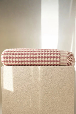 Pink Turkish cotton pom pom towel folded on a plinth - VivaMaison