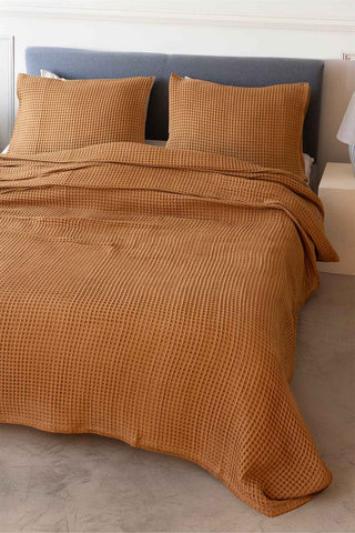 Natural waffle bedspread draped on bed showing honeycomb weave texture by Vivamaison