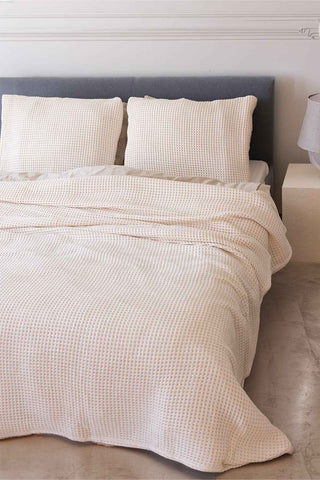 Natural waffle bedspread draped on bed showing honeycomb weave texture by Vivamaison